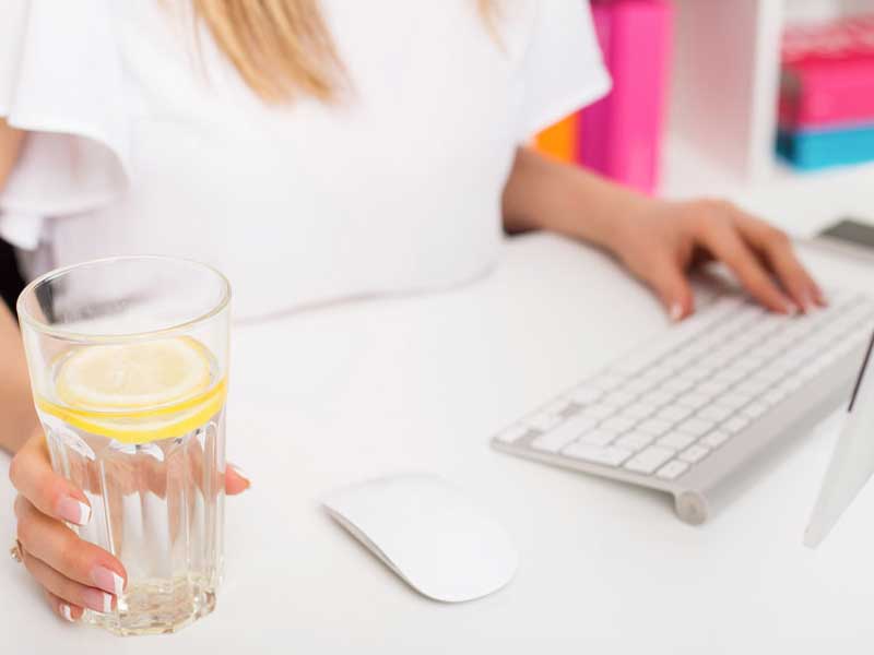 Cold glass of water and lemon in office
